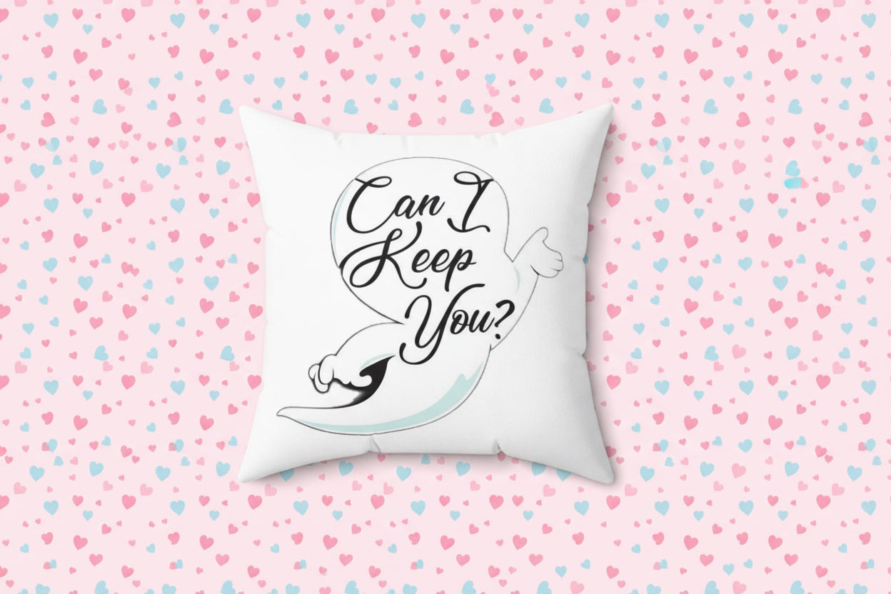 White pillow with a design of a hand holding a heart and text 'Can I Keep You?' on a white background